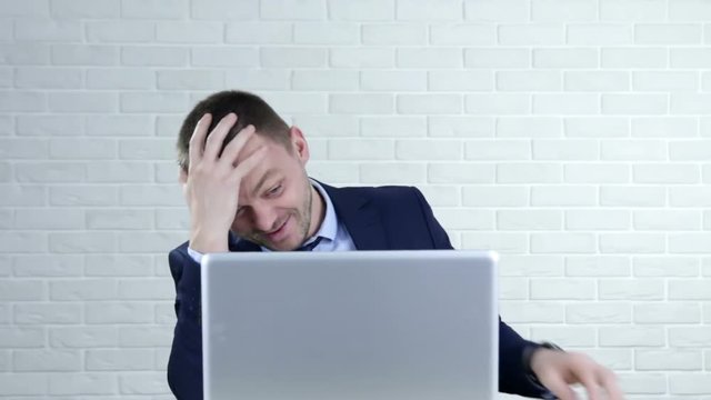 Funny young man laughing and pointing in the laptop