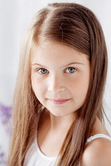Naklejka premium Portrait of pretty little emotion girl among violet flowers.Clouse up picture of beautiful smiling girl
