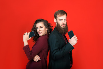 Businessman and businesswoman with gadgets isolated on red background.