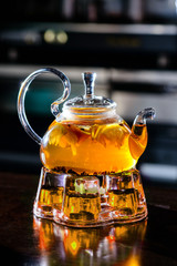 glass teapot with fruit hot tea in a cafe with orange