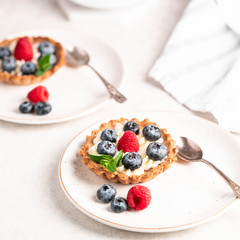 homemade tartlets with blueberries and raspberries on a light marble backdrop, overexposed