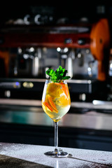 Closeup glass of white sparkling wine sangria decorated with citrus slices at bright bar counter background