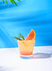 Cold and refreshing orange punch cocktail with orange slice on blue background. summer drink.