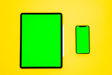 new tablet on a Yellow background with a keyboard and pen, and green screen top view