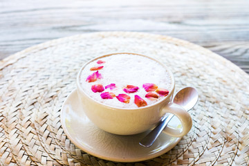 Cup pink cappuccino with foam decorated with rose petals wattled napkin spoon. Top vveiw. Cozy design