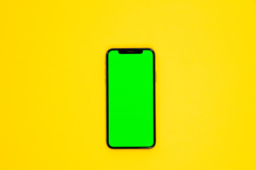 iPhone XS, smartphone, green screen on Yellow background top view