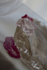 large transparent quartz crystal and purple crystals on a white diagonal background