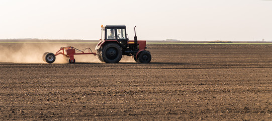  Farmer with tractor seeding sowing crops at agricultural field