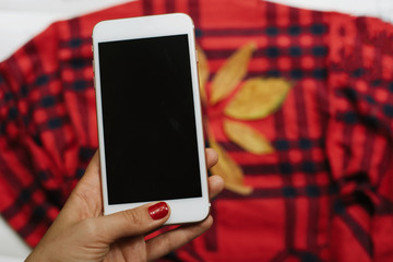 Female hands typing on mobile phone on red cell background. Autumn time.