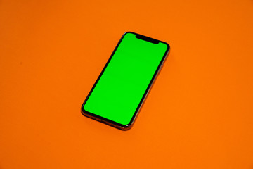 Phone smartphone, green screen on Orange background top view