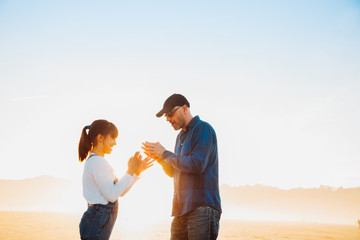 Father and daughter playing hands game on the beach at sunset