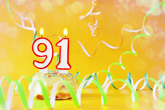 Ninety one years birthday. Cupcake with burning candles in the form of number 91. Bright yellow background with copy space