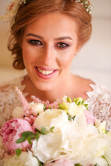 Fototapeta premium Happy blonde woman posing in w2edding dress with bouquet of flowers in hands
