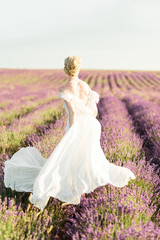 Fototapeta premium Stuning portrait of girl in light dress in lavender field on sunset