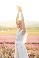 Fototapeta na wymiar Stuning portrait of girl in light dress in lavender field on sunset