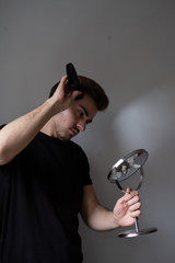 Man shaving his hair off with an electric razor. Looking to a mirror. Lifestyle.