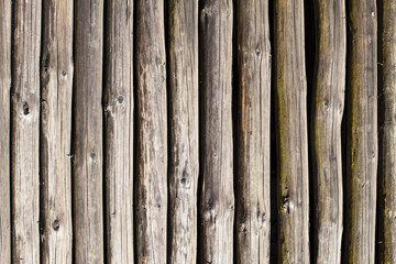 Gray wooden wall made with small tree logs. Natural wood texture background.