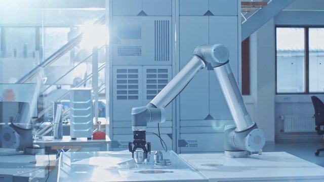 In the Bright Robotic Industry Engineering Facility Robot Arm Picks Up Metal Component Moves it Into Place. Tech Industrial Technology Using Modern Machine Learning, Neural Networking for Efficiency.
