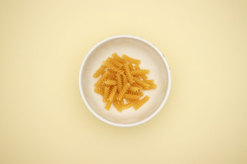 Pasta in white dish on yellow background