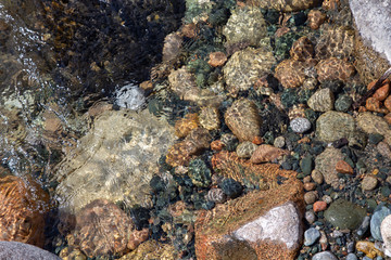 Water in the mountain raging river. Beautiful natural background of stones and water. Texture of clear water and fast river. Background to insert text. Tourism and travel.