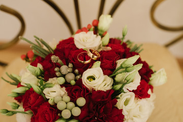 Beautiful wedding bouquet with red and white rouses and rings on top. Close up