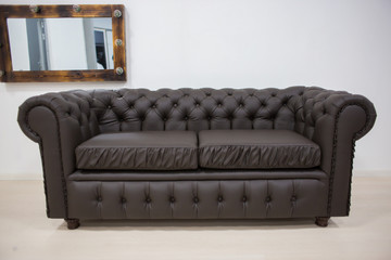 The brown leather sofa costs in the light room with a mirror