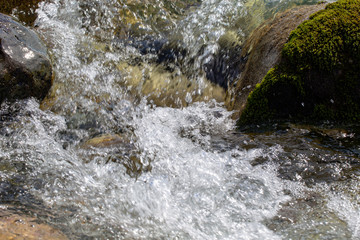 Water in the mountain raging river. Beautiful natural background of stones and water. Texture of clear water and fast river. Background to insert text. Tourism and travel.