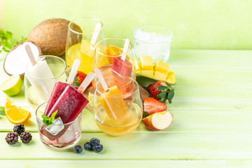 Selection of colourful ice pops and ingredients on green wood background