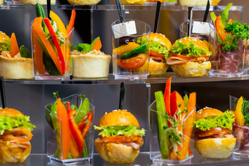 Mini canapes with cheese salads meat and seafood in plastic cups. 