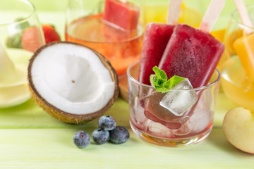 Selection of colourful ice pops and ingredients on green wood background