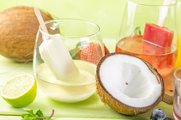 Selection of colourful ice pops and ingredients on green wood background