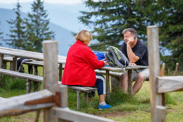 Mature Man and woman resting at camp in mountains