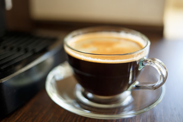 Cup of fresh brewed coffee near the coffee machine
