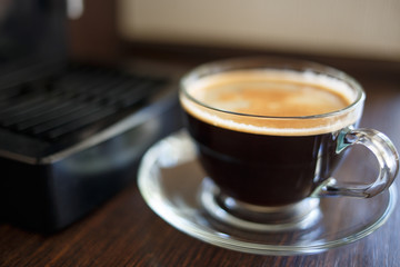 Cup of fresh brewed coffee near the coffee machine