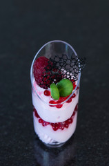 Mini canapes in plastic cups on a dark background of granite stone.