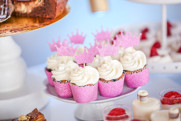 Vanilla pink cupcakes with crown decoration, selective focus