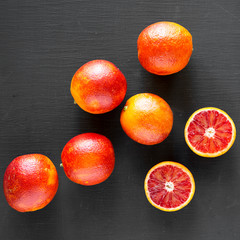 Whole and halved blood oranges on black table, top view. Flat lay, overhead, from above. Close-up.