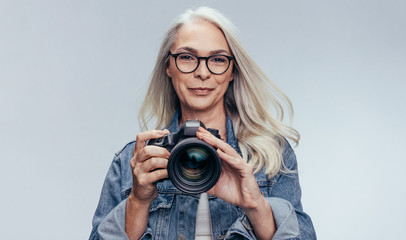 Porfessional female photographer during a photo shoot - obrazy, fototapety, plakaty