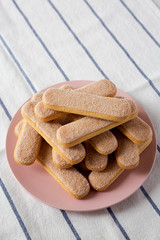 Savoiardi or ladyfingers cookies on pink plate, low angle view. Closeup. Copy space.