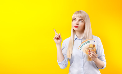 Portrait of a cheerful young blonde girl holding money .