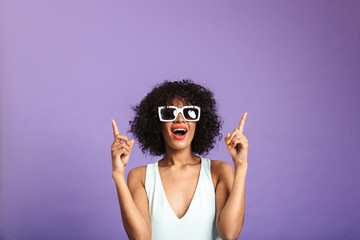 Cheerful pretty woman in sunglasses pointing up with open mouth