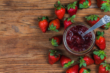 Jar of strawberry jam on  wooden background from top view