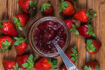 Jar of strawberry jam on  wooden background from top view