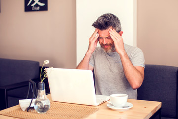Man having a headache in front of laptop
