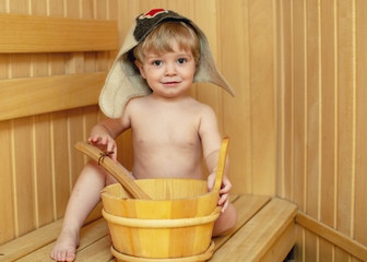 Beauty, healthcare. baby Boy relaxing in the sauna Toddler with broom and hat in russian sauna or...
