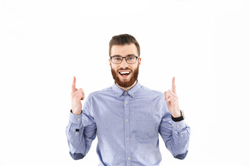 Naklejka premium Cheerful bearded elegant man in eyeglasses pointing up