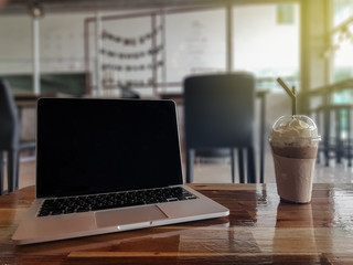 Laptop with coffee on table on cafe background