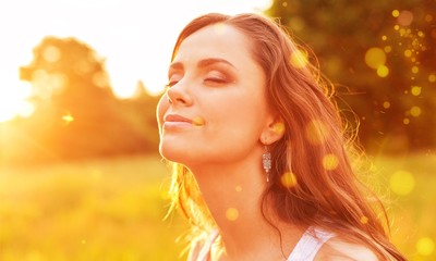 Fototapeta premium Young woman on field under sunset light