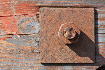 Large rusty nut holds wood  aged painted planks together