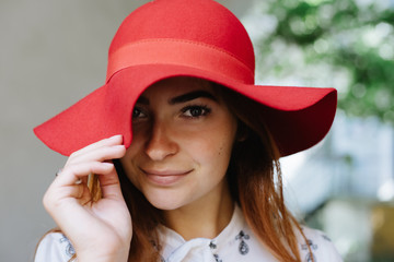 portrait of young beautiful girl wearing a red hat in white blouse in old town street, outdoor